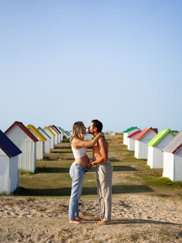 Séance couple sur la plage, devant les cabines colorées