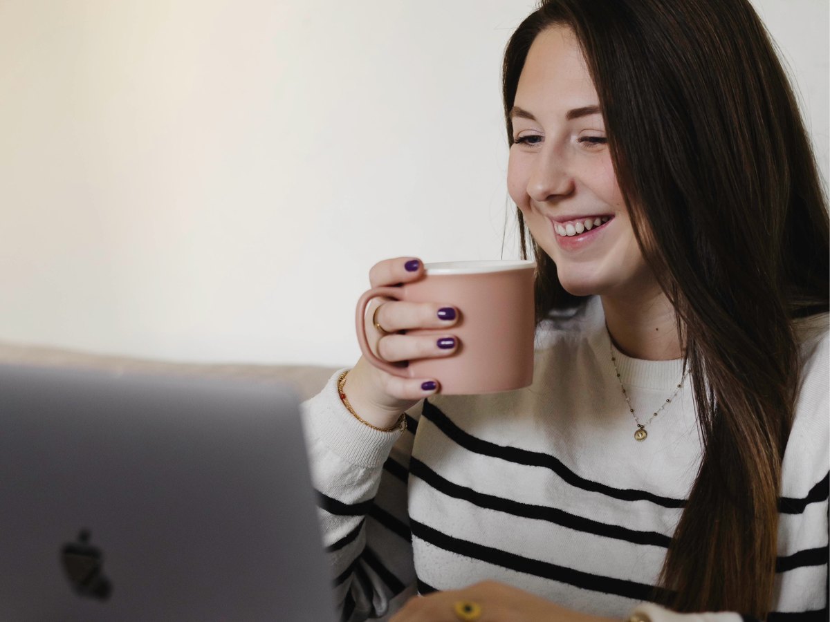 Marion à son bureau, souriante devant son ordinateur, un café à la main